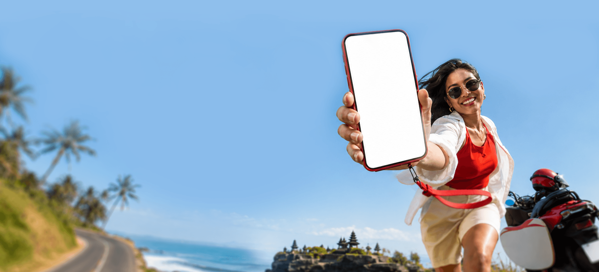 Two travelers smiling at a phone in front of a Balinese temple by the sea