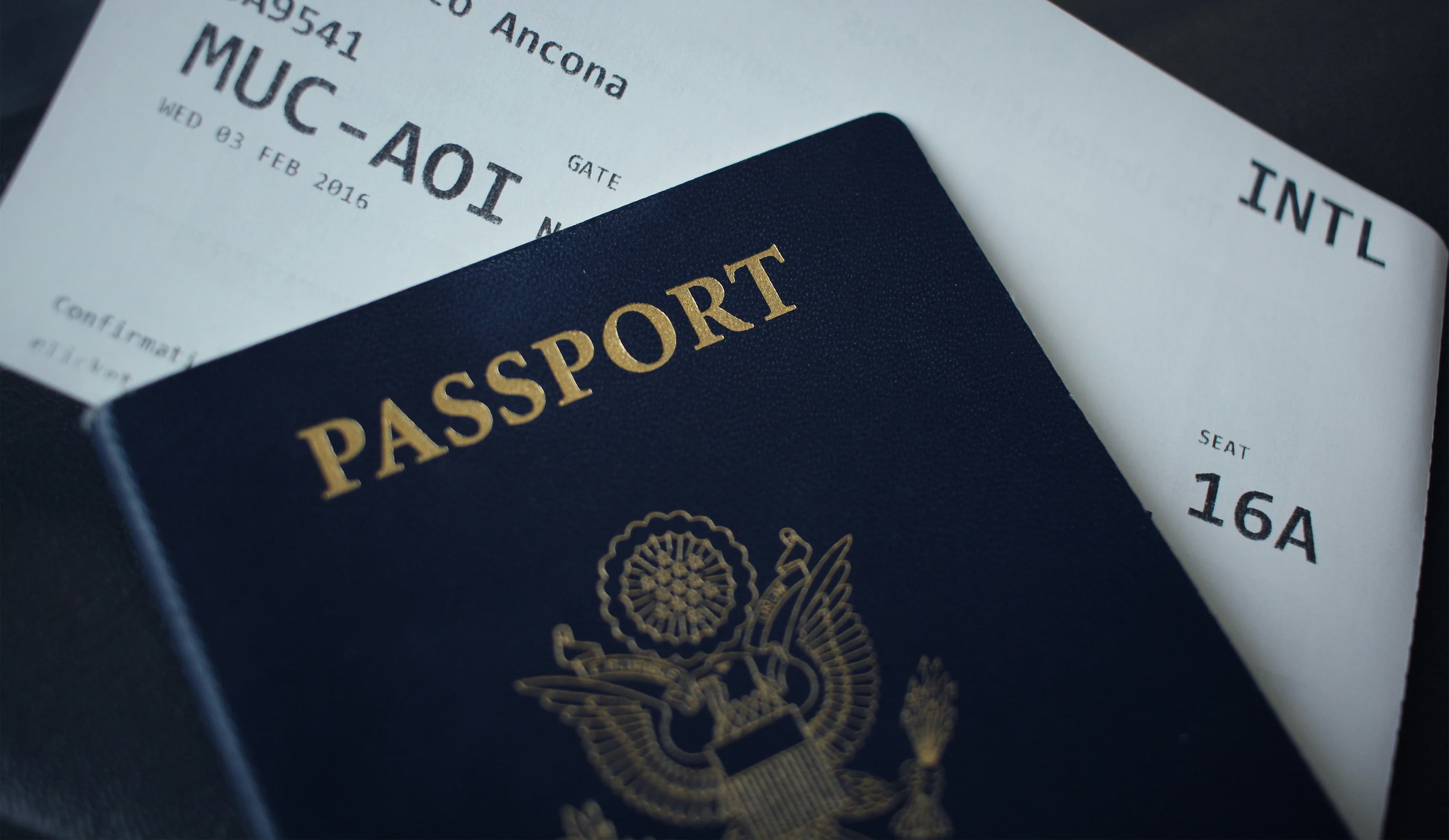 A blue US passport rests on top of an airline boarding pass.